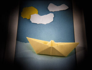 Origami boat on a paper river, under a paper sky.